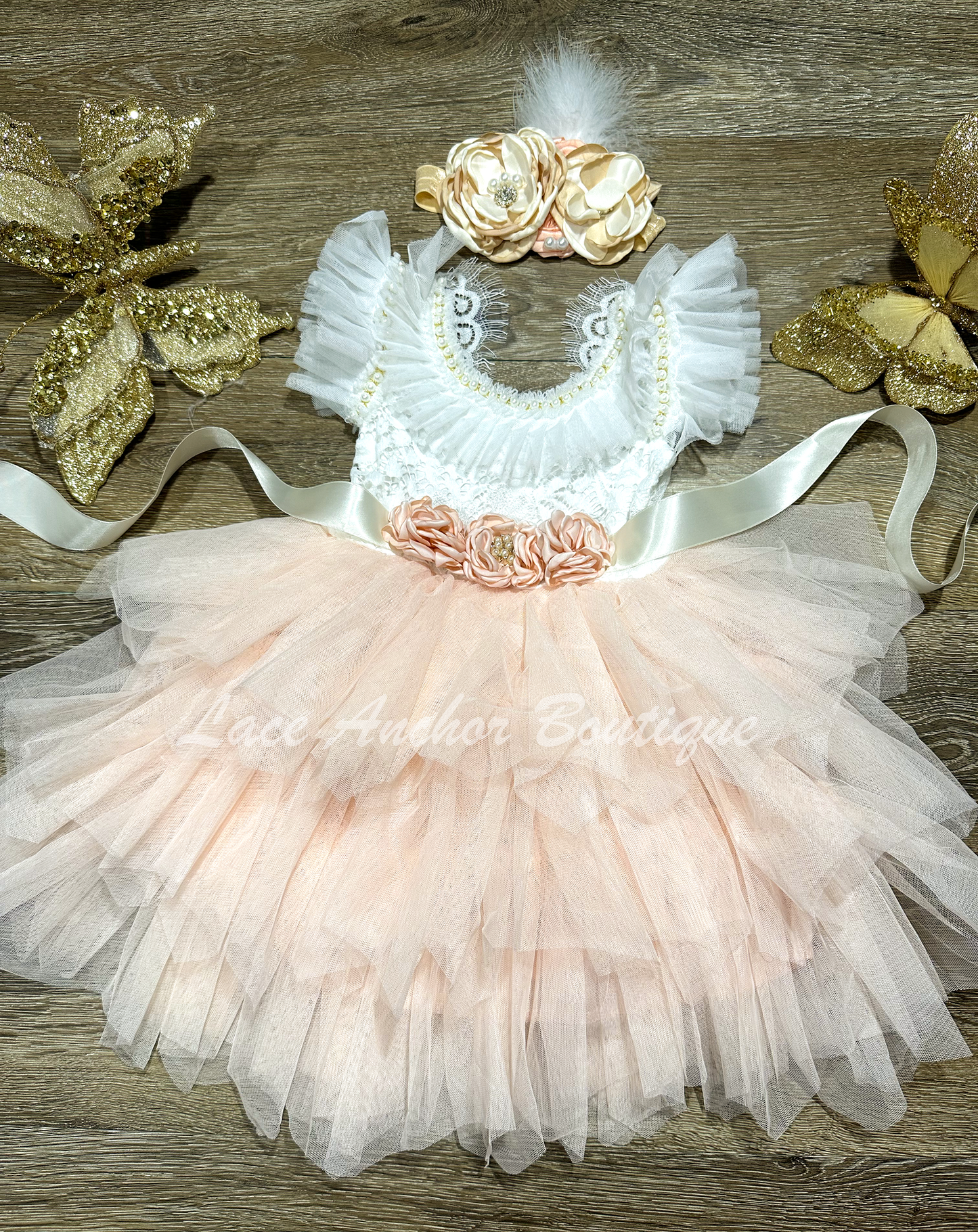 lace and tulle flower girls dress. white lace top with ruffled tulle sleeves and beaded pearl and rhinestone detailing with blush pink layered tulle skirt and silk flower tied sash.