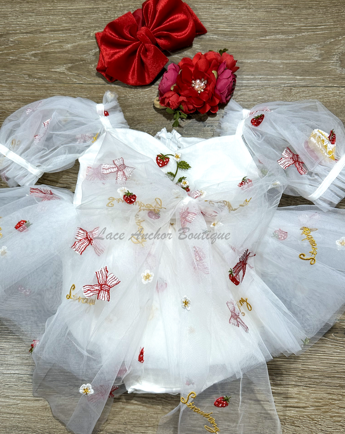 white romper with strawberries, bows, and strawberry shortcake embroidered print with large fluffy tied bow and puff sleeves.