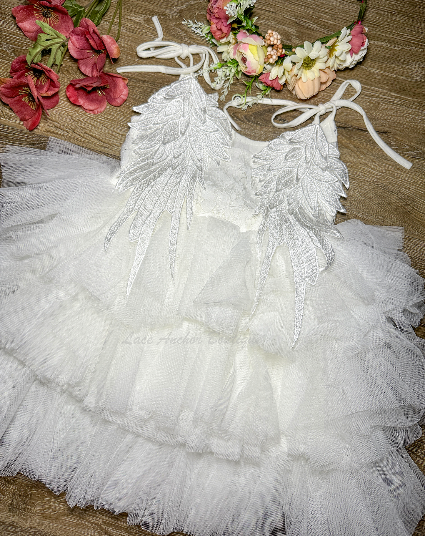 all white girls dress with layered ruffled tulle skirt, lace top, tied shoulders, and embroidered angel wings on backside.