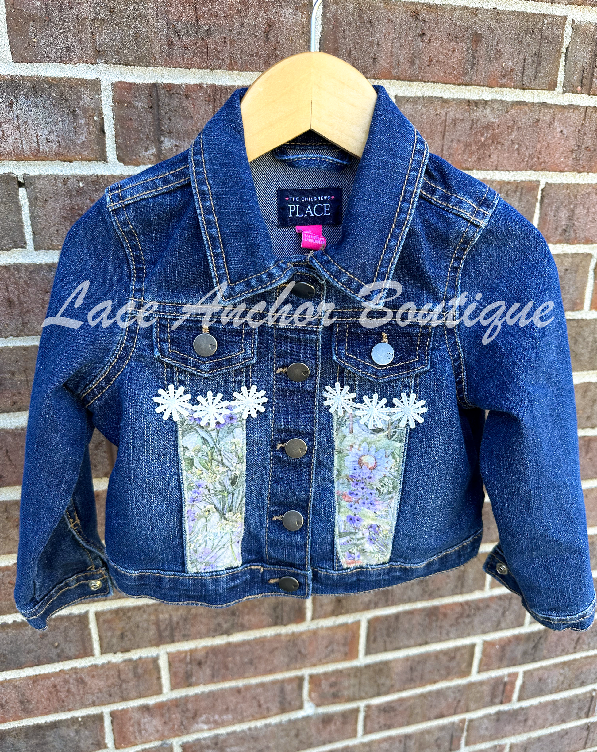custom handmade upcycle toddler girls denim jacket with floral daisy fabric patch and white flower trim.