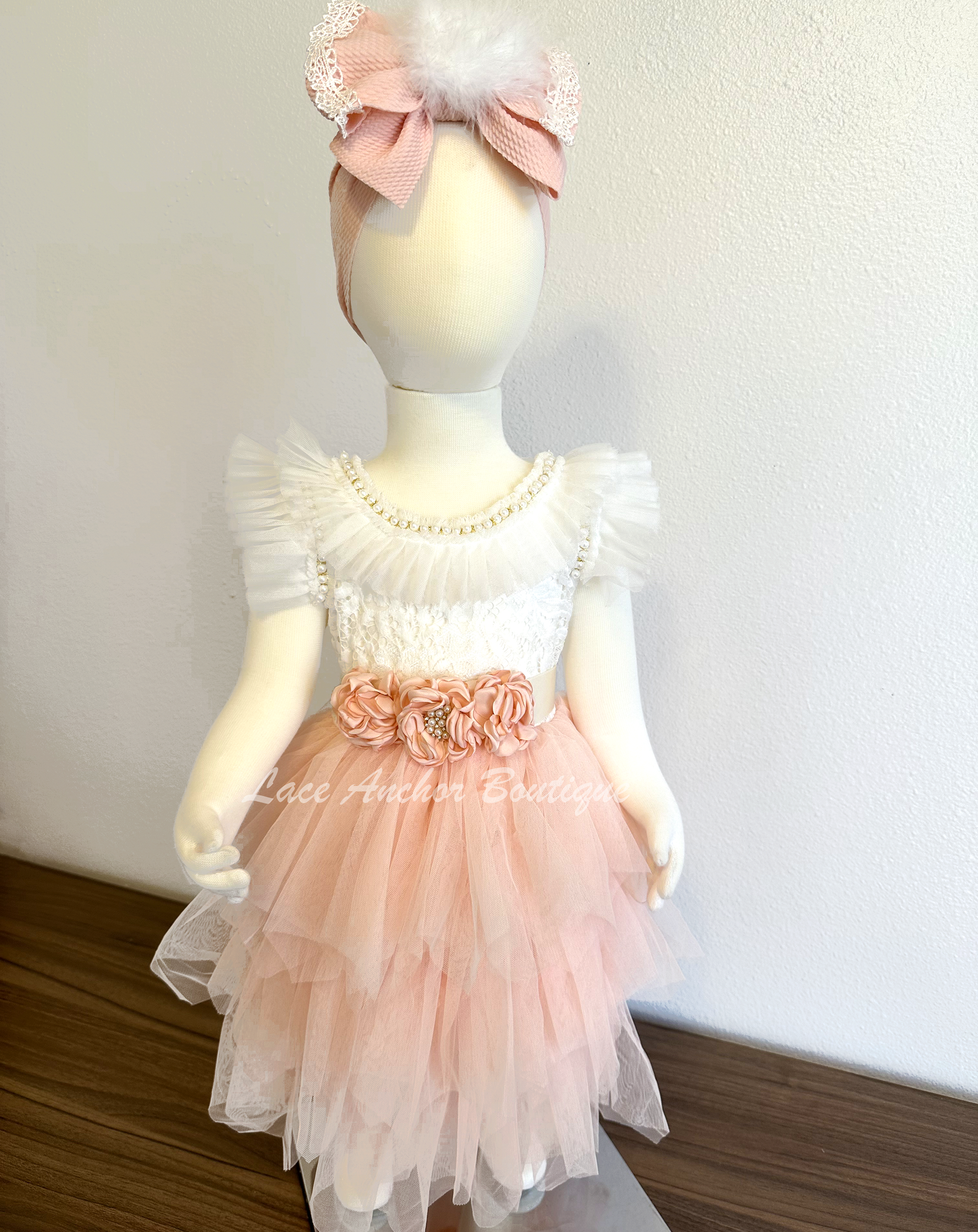 lace and tulle flower girls dress. white lace top with ruffled tulle sleeves and beaded pearl and rhinestone detailing with blush pink layered tulle skirt and silk flower tied sash.