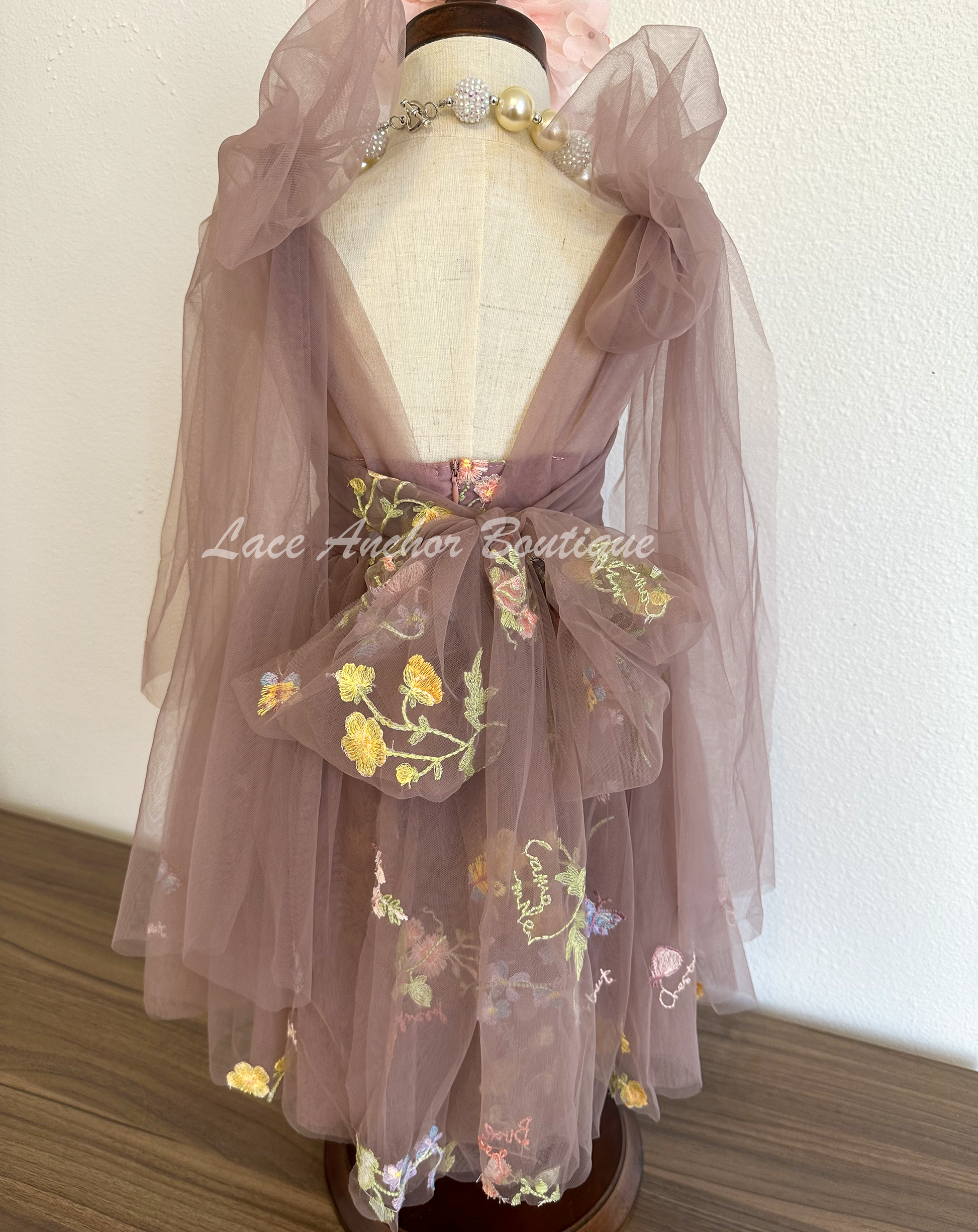 toddler youth puffy tied shoulder flower girl dress with large tied bow tied at waist. Outfits in deep plum purple with emboridered floral print.
