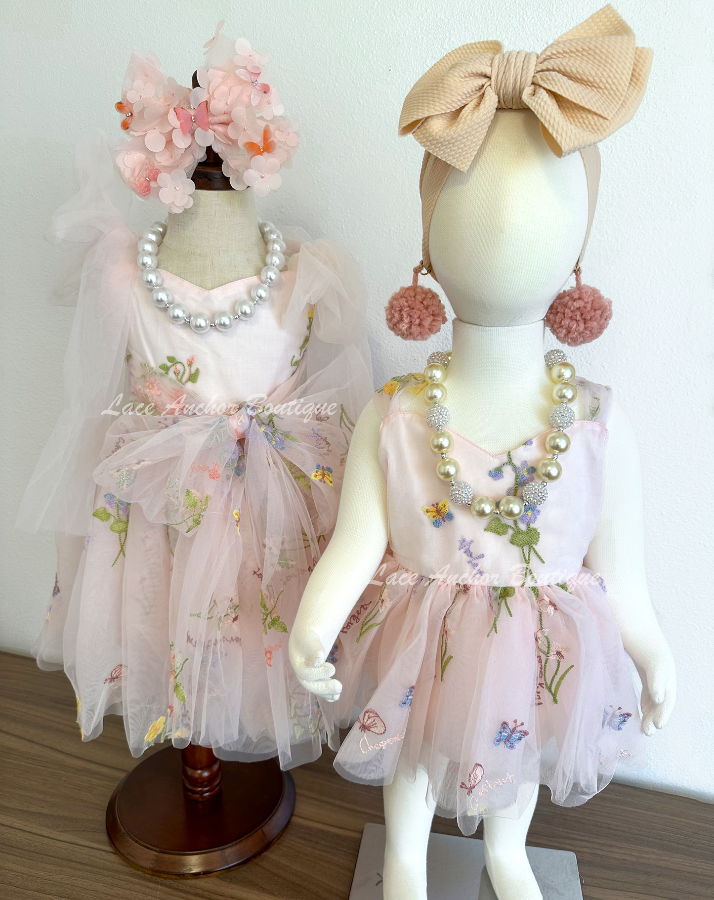 toddler youth puffy tied shoulder flower girl dress with large tied bow tied at waist. Baby girls romper with tied back fluffy bow. Outfits in light blush pink with embroidered floral print.