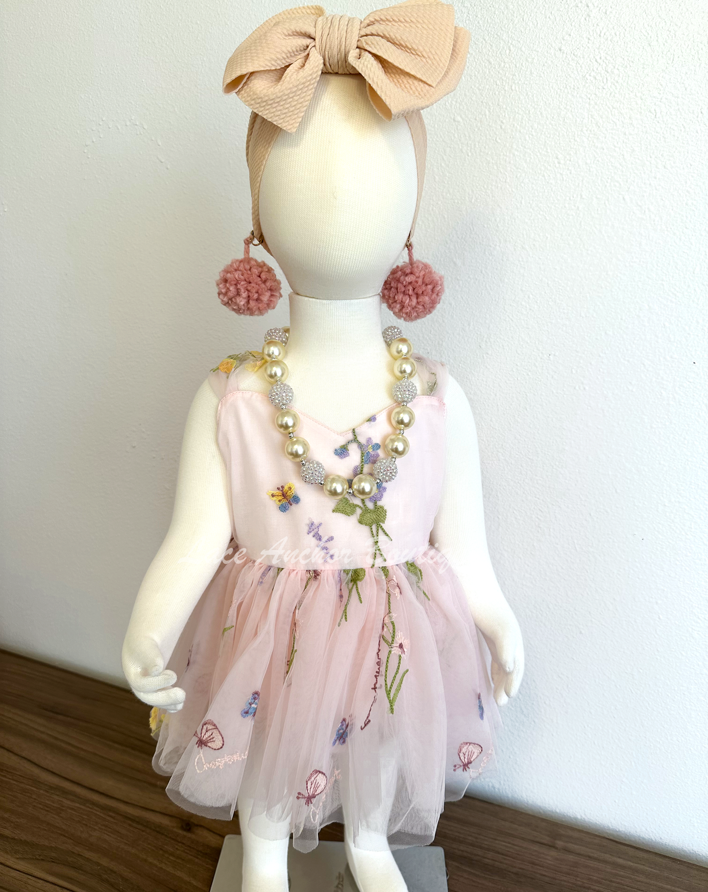 Baby girls romper with tied back fluffy bow. Outfits in light blush pink with embroidered floral print.