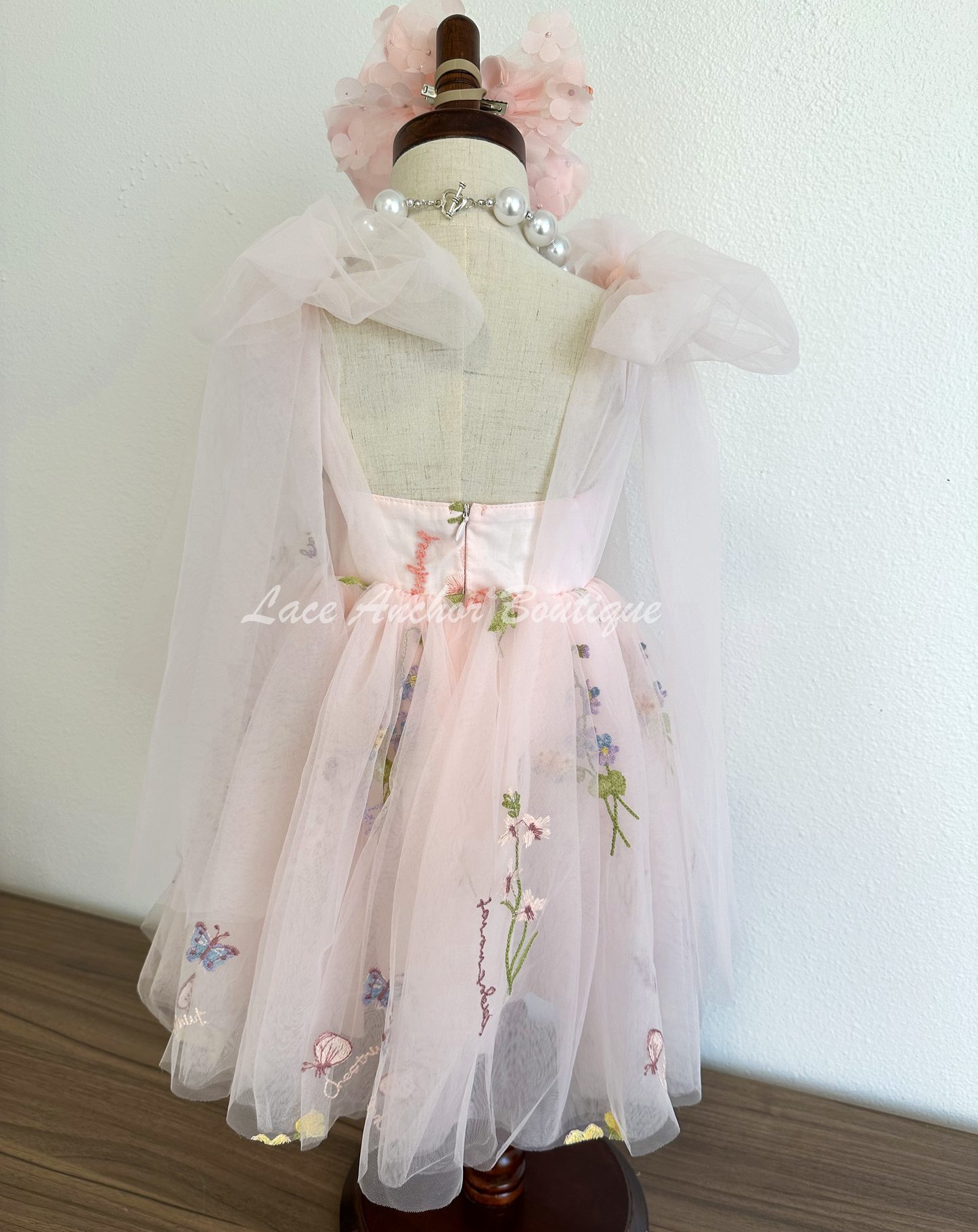 toddler youth puffy tied shoulder flower girl dress with large tied bow tied at waist. Outfits in light blush pink with emboridered floral print.