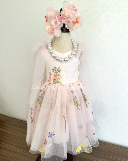 toddler youth puffy tied shoulder flower girl dress with large tied bow tied at waist. Outfits in light blush pink with embroidered floral print.