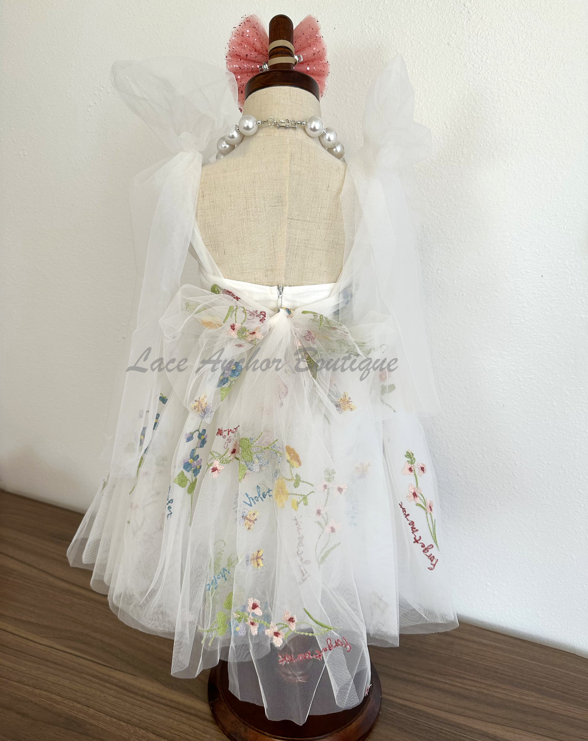 toddler youth puffy tied shoulder flower girl dress with large tied bow tied at waist. Outfits in white with embroidered floral print.
