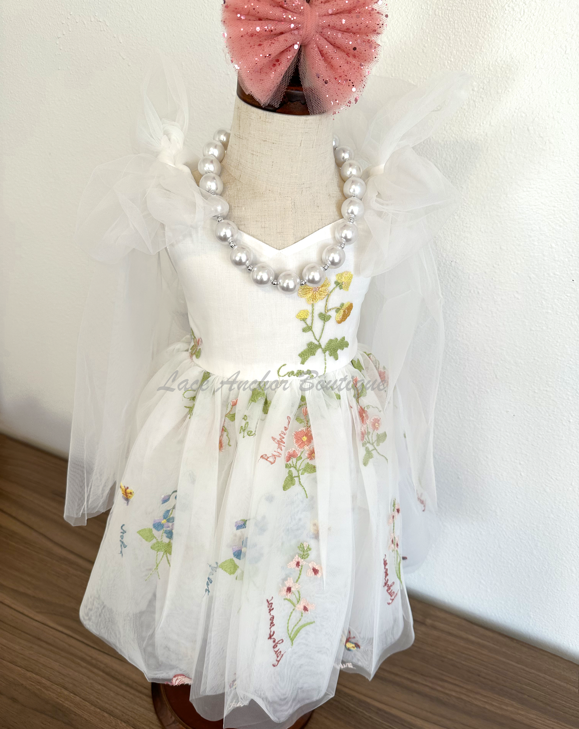oddler youth puffy tied shoulder flower girl dress with large tied bow tied at waist. Outfits in white with embroidered floral print.