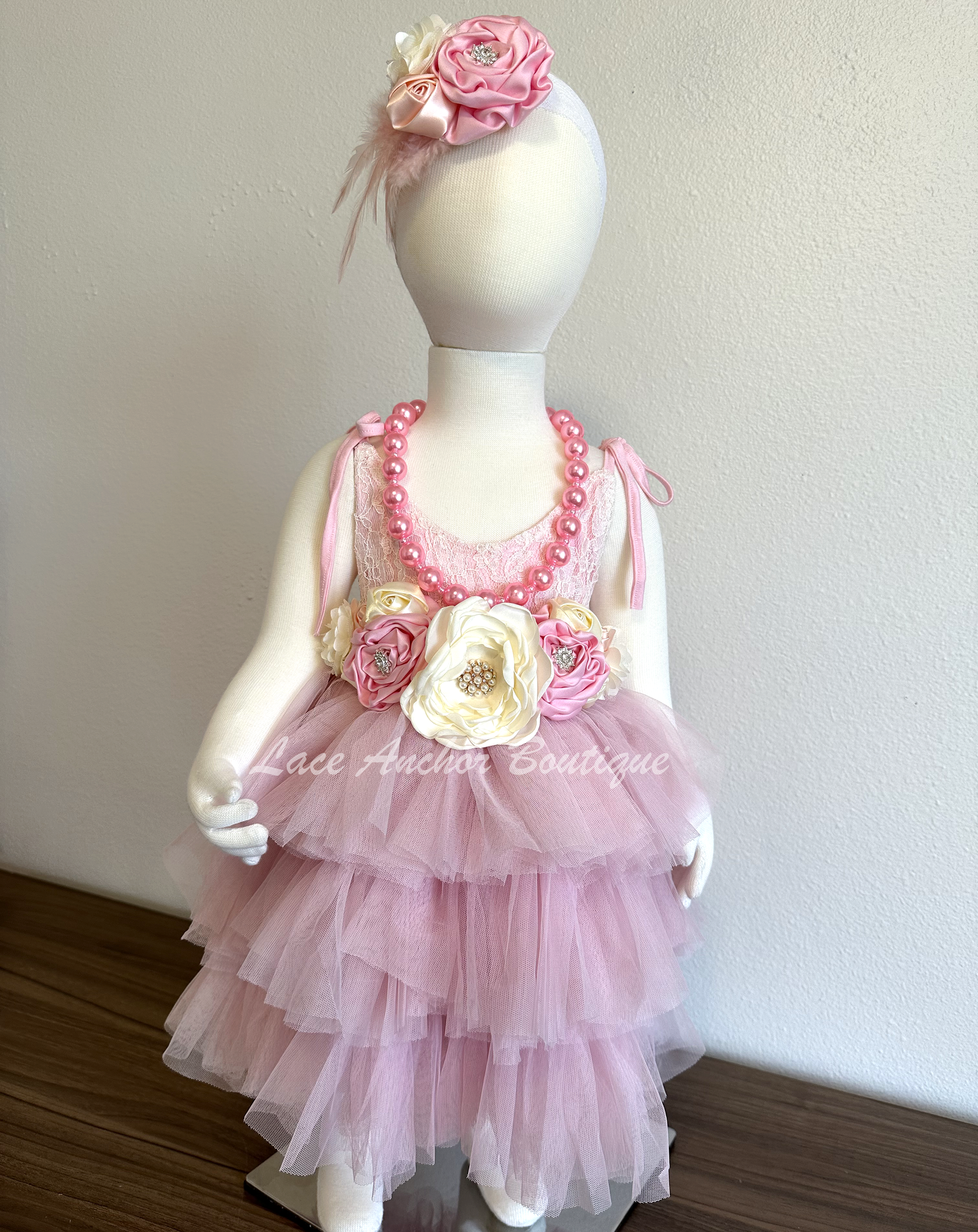 Light pink toddler girls dress with lace top, tied straps, layered ruffled tulle skirt, and silky floral tied  sash. Girls flower girl dress.