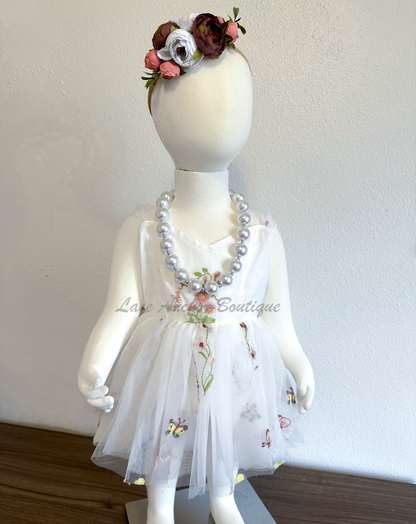 Baby girls romper with tied back fluffy bow. Outfits in white with embroidered floral print.