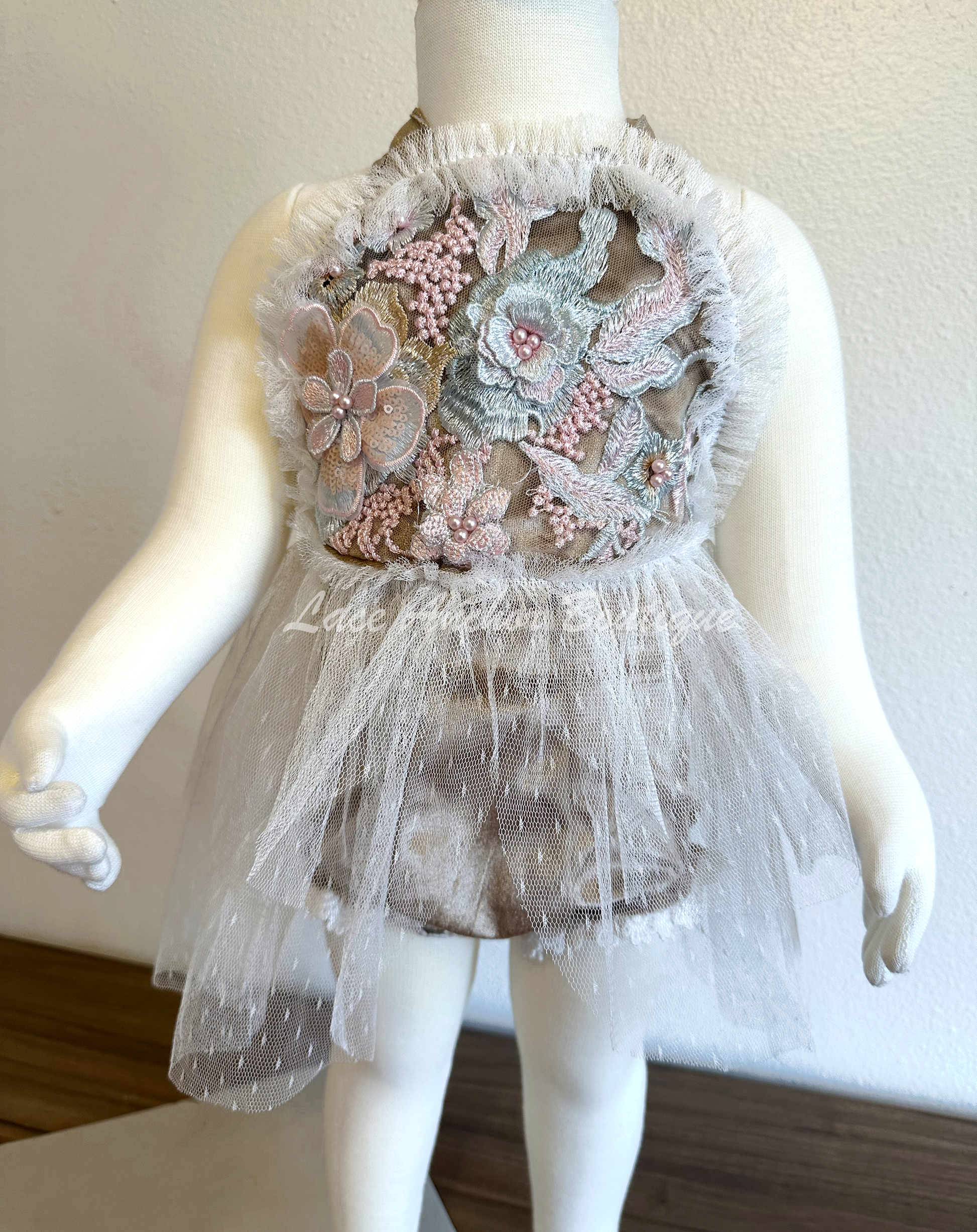 baby girls aupe light brown romper with lace trim, ruffled detail, tulle skirt, and embroidered floral flower top with tied halter straps. Baby girl flower girl outfit.