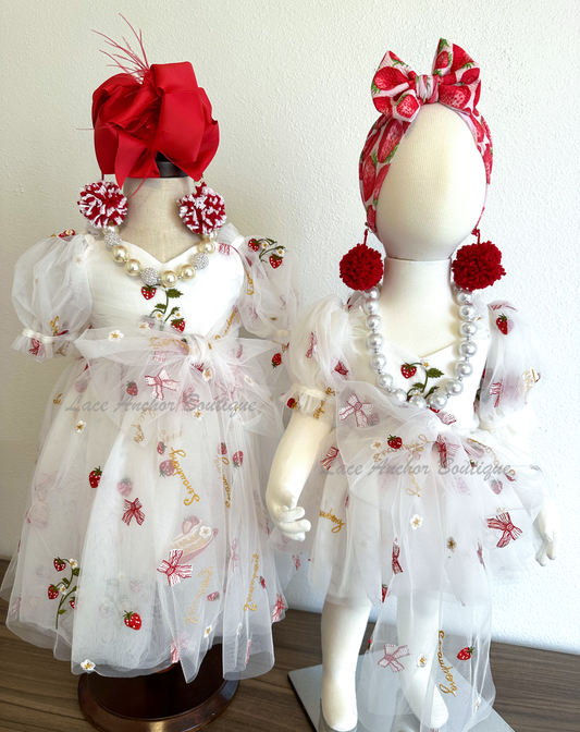 white dress or rompers with strawberries, bows, and strawberry shortcake embroidered print with large fluffy tied bow and puff sleeves.
