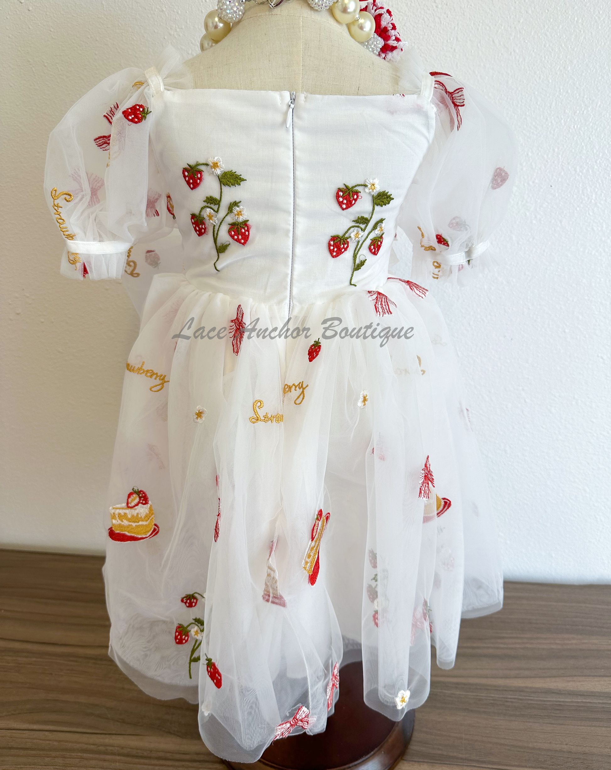 white dress with strawberries, bows, and strawberry shortcake embroidered print with large fluffy tied bow and puff sleeves.