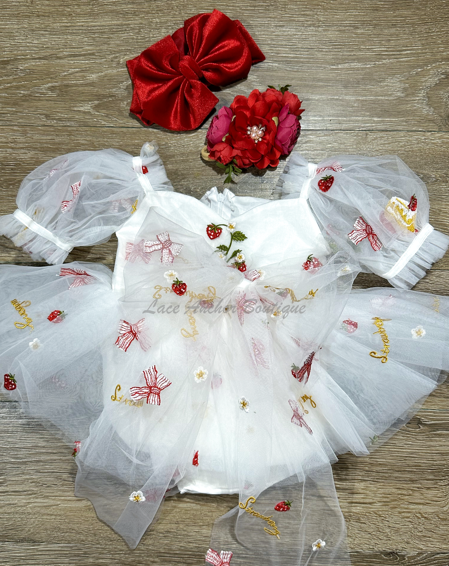 white romper with strawberries, bows, and strawberry shortcake embroidered print with large fluffy tied bow and puff sleeves.