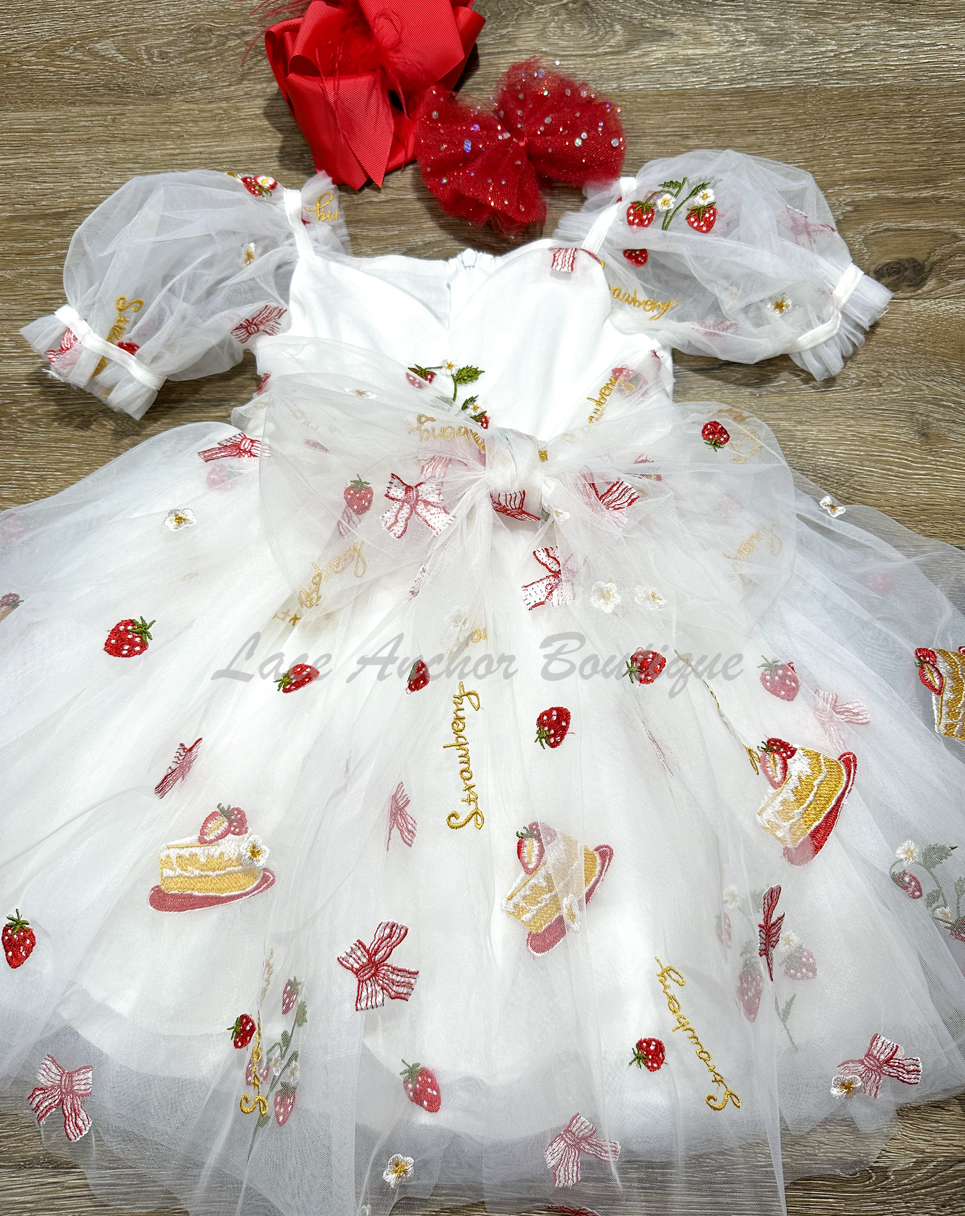 white dress with strawberries, bows, and strawberry shortcake embroidered print with large fluffy tied bow and puff sleeves.