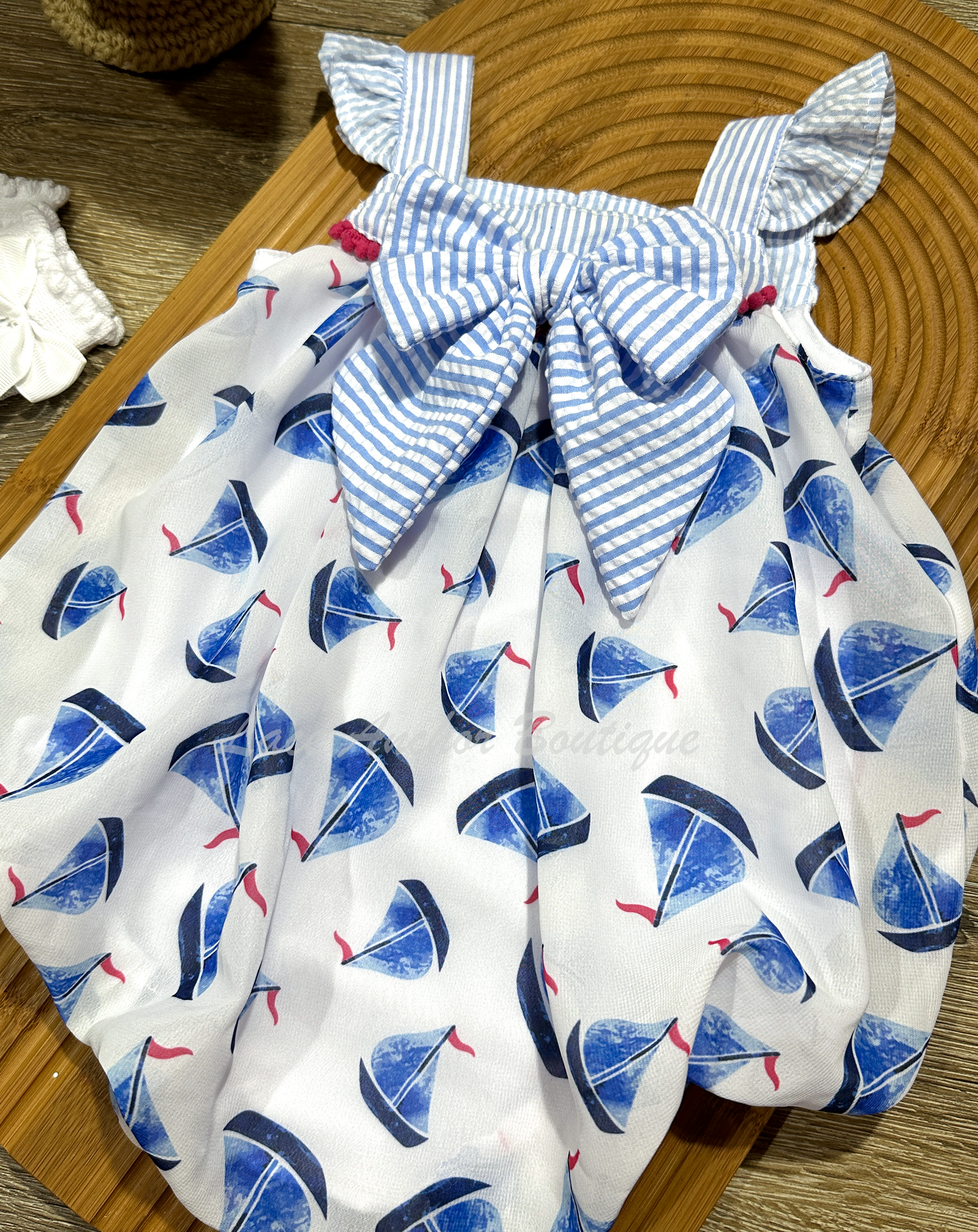 upcycled thrifted white bubble baby girls romper with blue and white gingham top, gingham sailor bow, and blue and hot pink sailboat print all over.