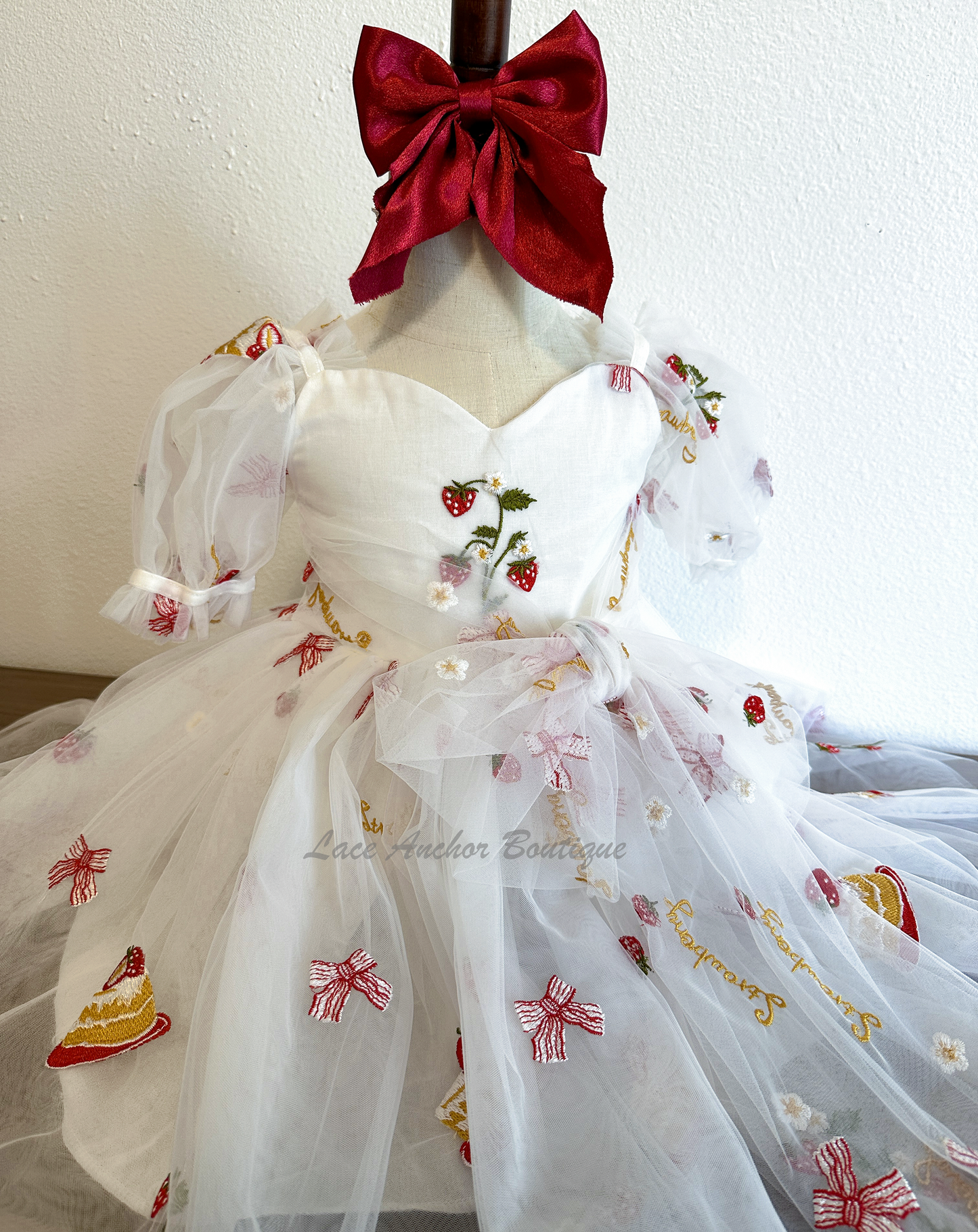 white dress with strawberries, bows, and strawberry shortcake embroidered print with large fluffy tied bow and puff sleeves.