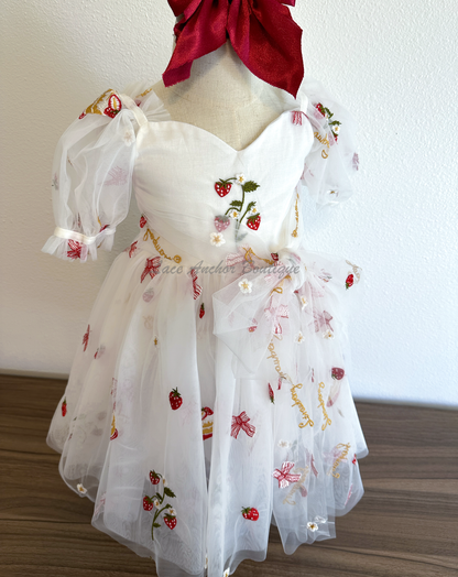 white dress with strawberries, bows, and strawberry shortcake embroidered print with large fluffy tied bow and puff sleeves.