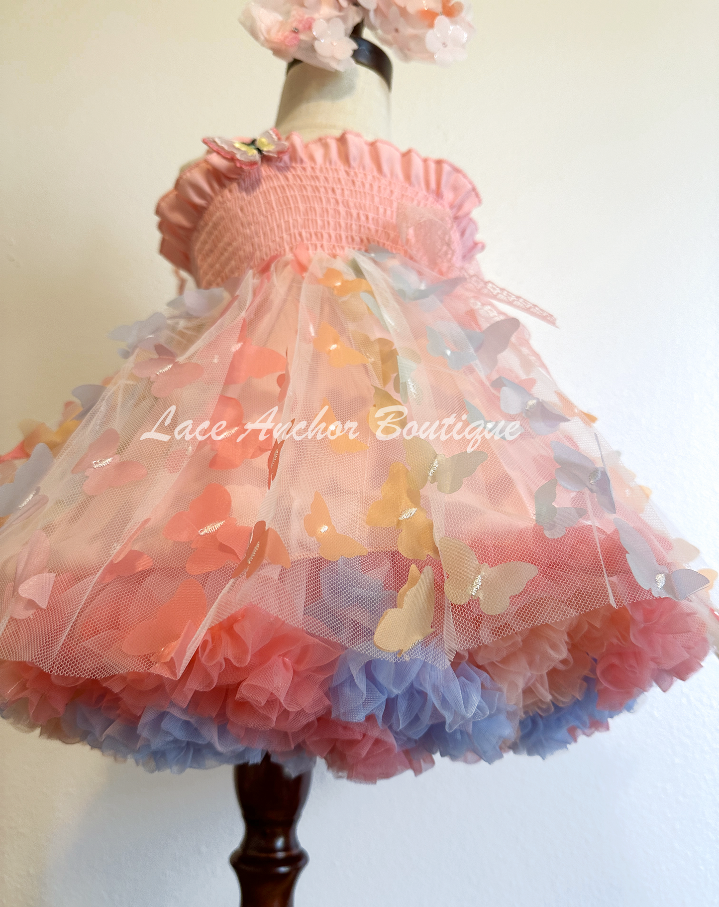 Light blush pale pink rainbow girls butterfly wing fairy dress in pink on model child toddler. Has butterflies all over skirt.