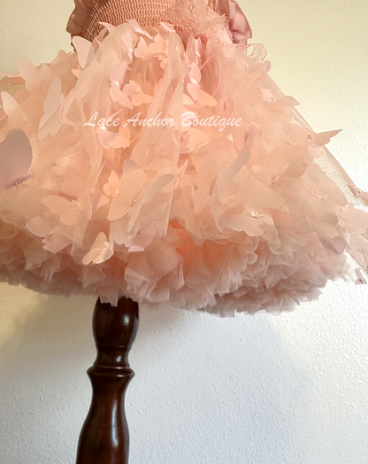 Light blush pale pink girls butterfly wing fairy dress in pink on model child toddler. Has butterflies all over skirt.