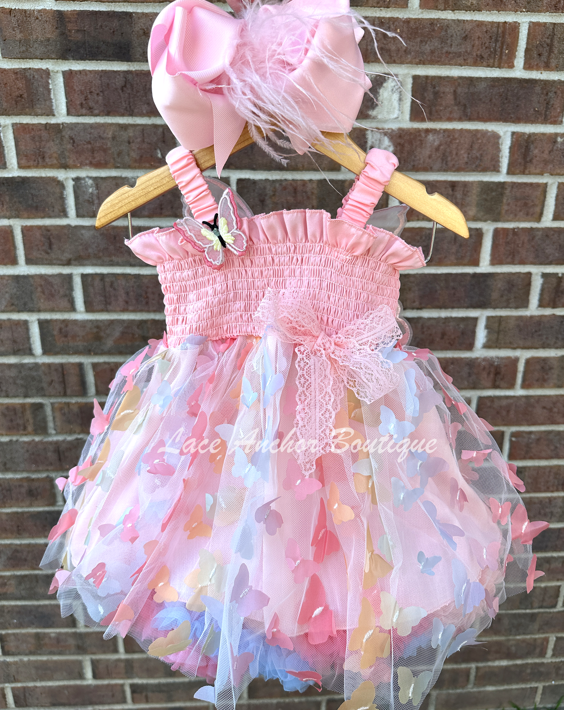 Light blush pale pink rainbow girls butterfly wing fairy dress in pink on model child toddler. Has butterflies all over skirt.