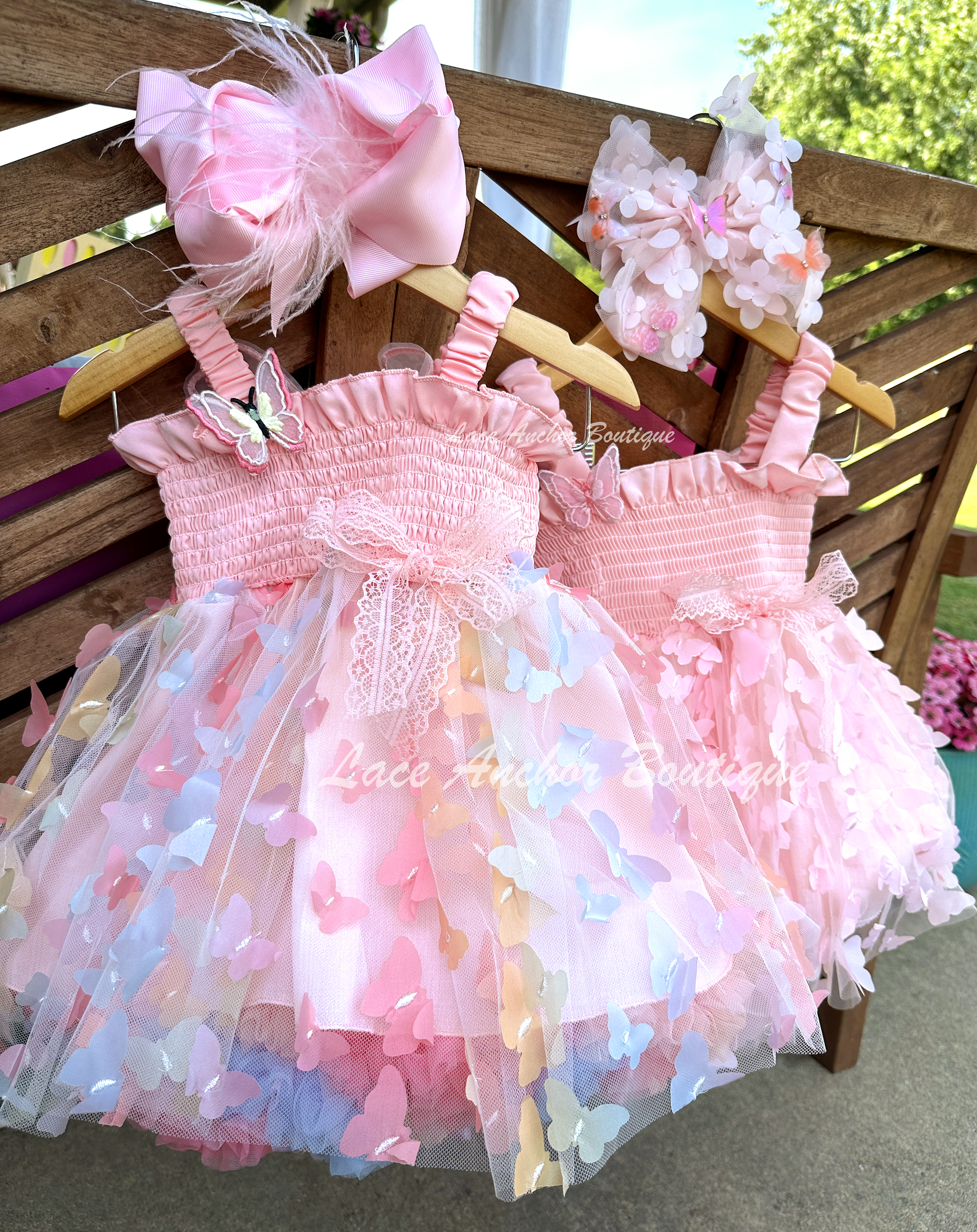 Light blush pale pink rainbow girls butterfly wing fairy dress in pink on model child toddler. Has butterflies all over skirt.