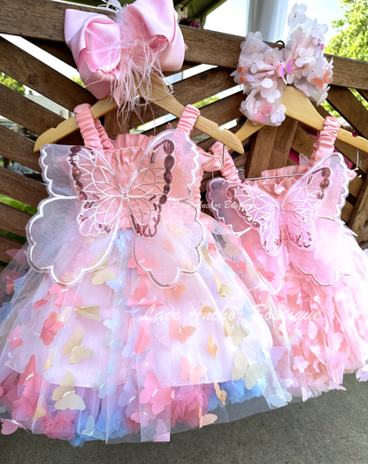 Light blush pale pink rainbow girls butterfly wing fairy dress in pink on model child toddler. Has butterflies all over skirt.