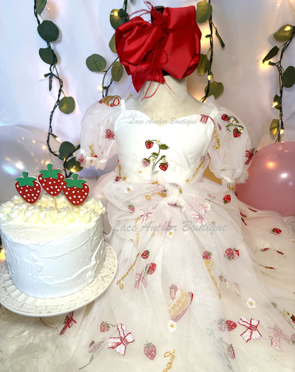 white dress with strawberries, bows, and strawberry shortcake embroidered print with large fluffy tied bow and puff sleeves.