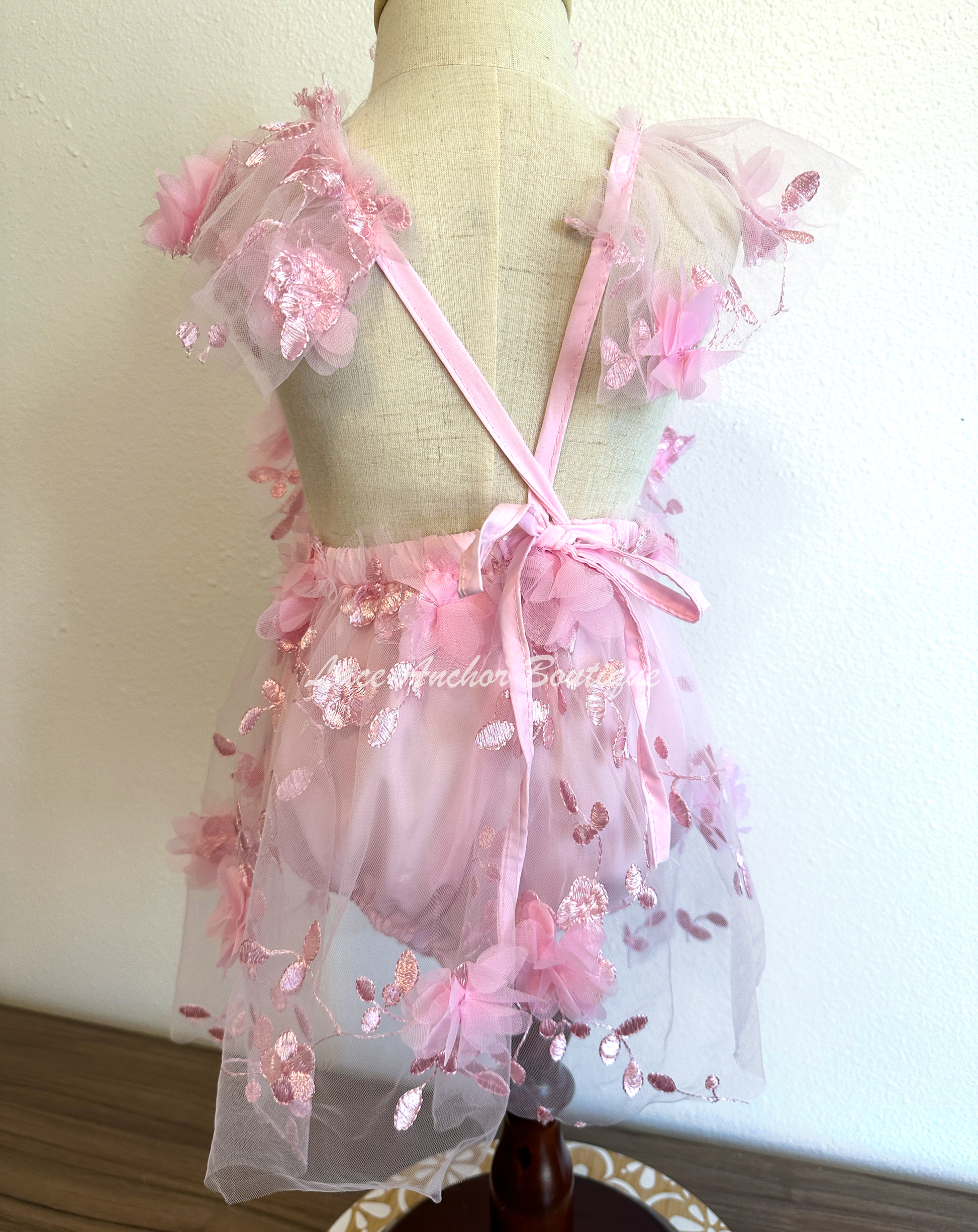 light pink baby girl romper. Butterfly floral romper dress with flutter sleeves, embroidered flowers, and butterflies.