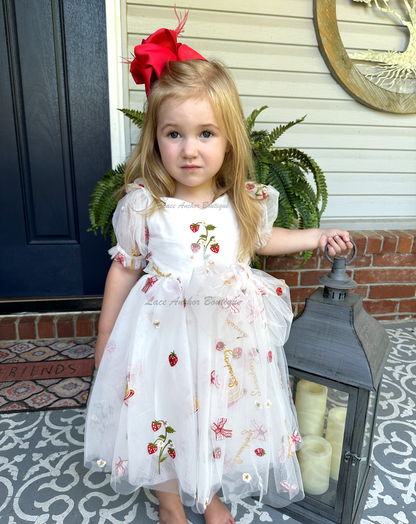 white dress with strawberries, bows, and strawberry shortcake embroidered print with large fluffy tied bow and puff sleeves.