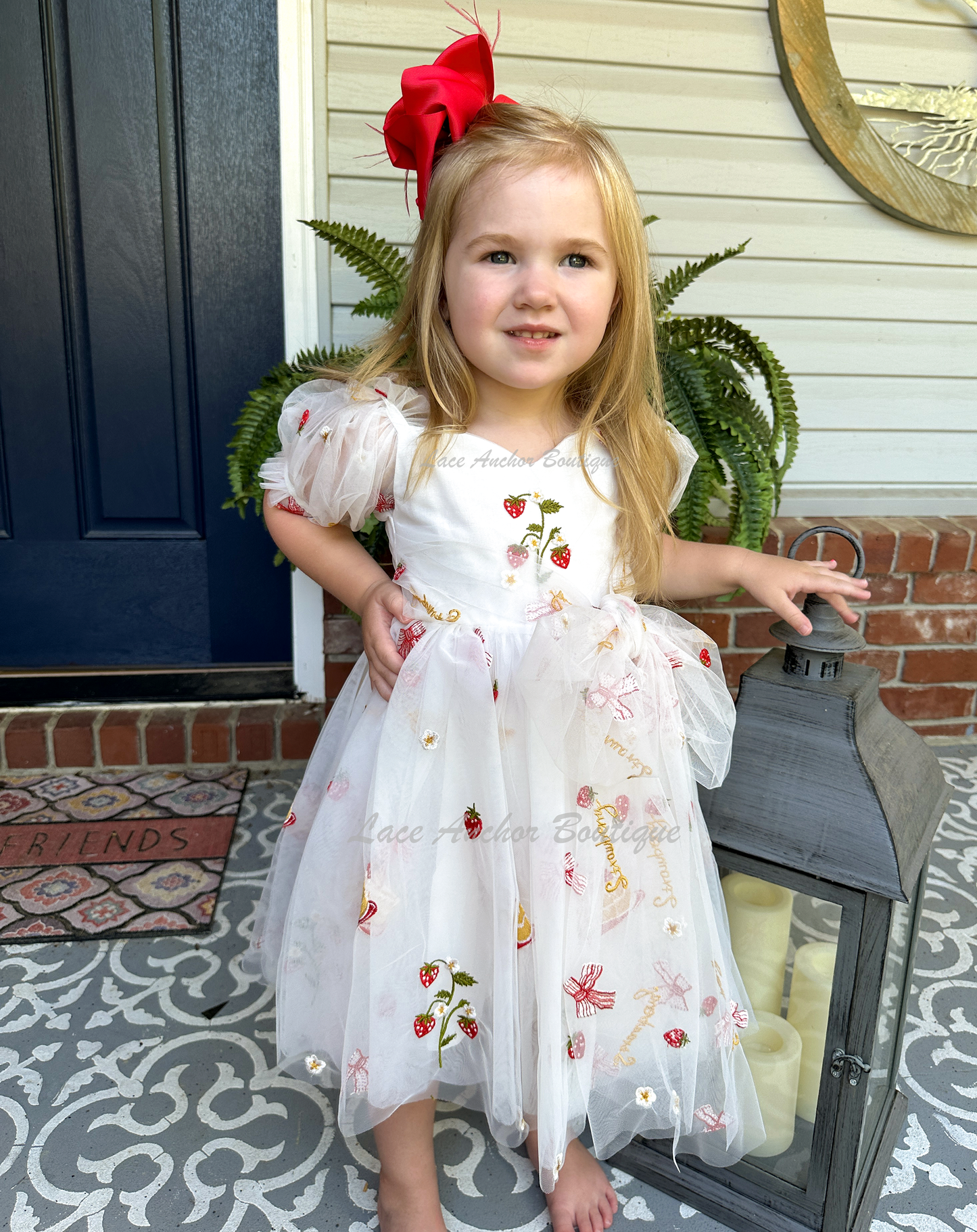 white dress with strawberries, bows, and strawberry shortcake embroidered print with large fluffy tied bow and puff sleeves.