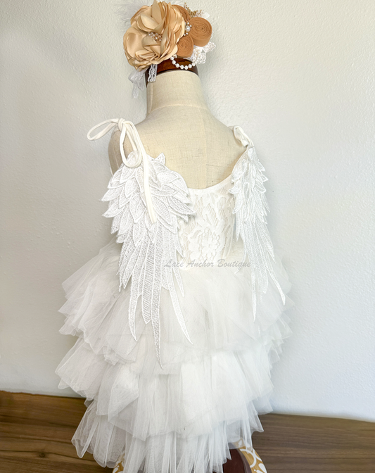 all white girls dress with layered ruffled tulle skirt, lace top, tied shoulders, and embroidered angel wings on backside.