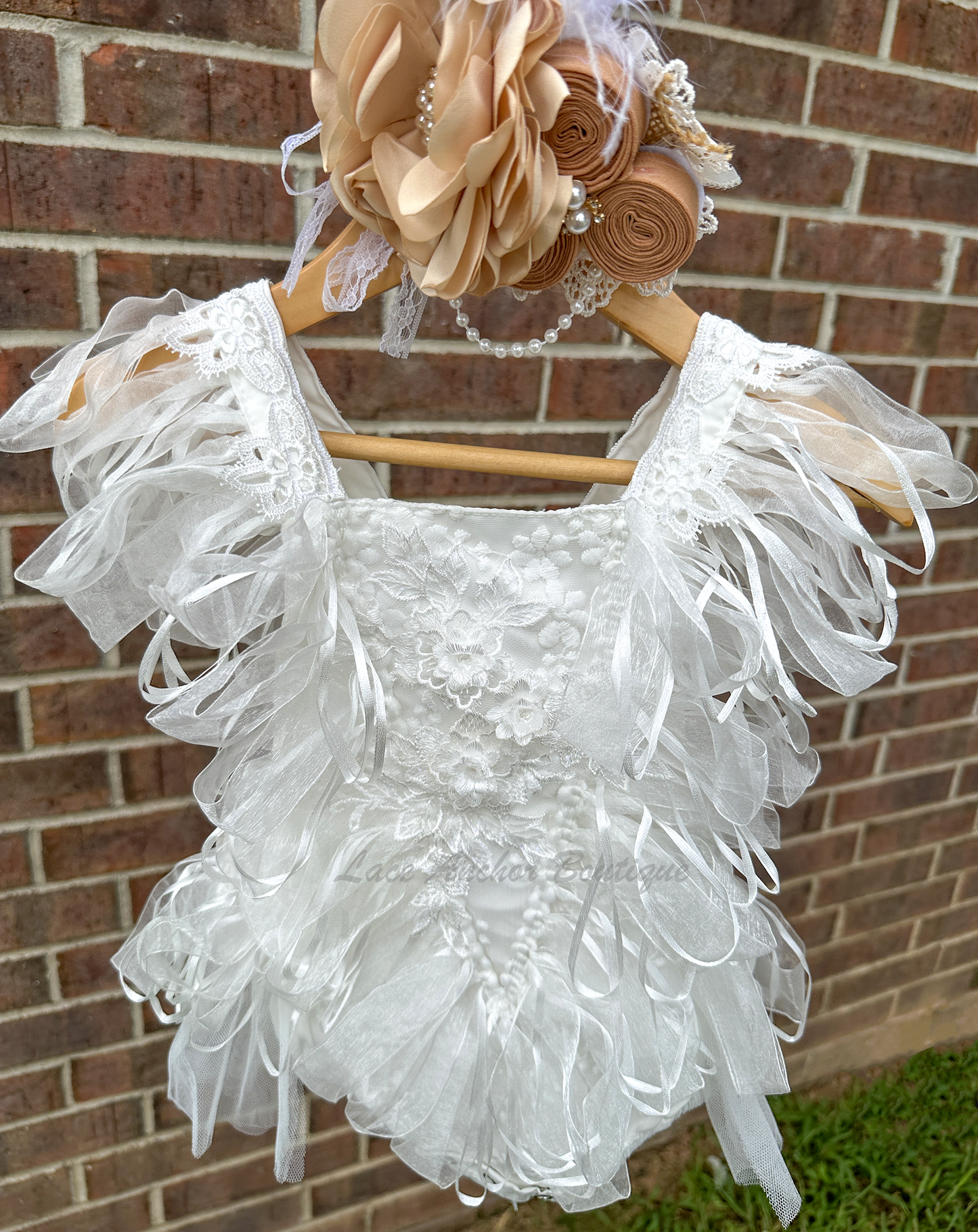 white baby girls romper with tulle half skirt, ribbon loop details, and embroidered floral applique across front