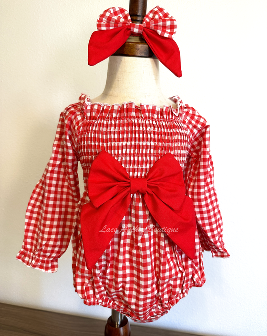 red and white gingham print long sleeve baby girls romper with smocked top and large red sailor bow on chest. Comes with matching bow on nylon band.