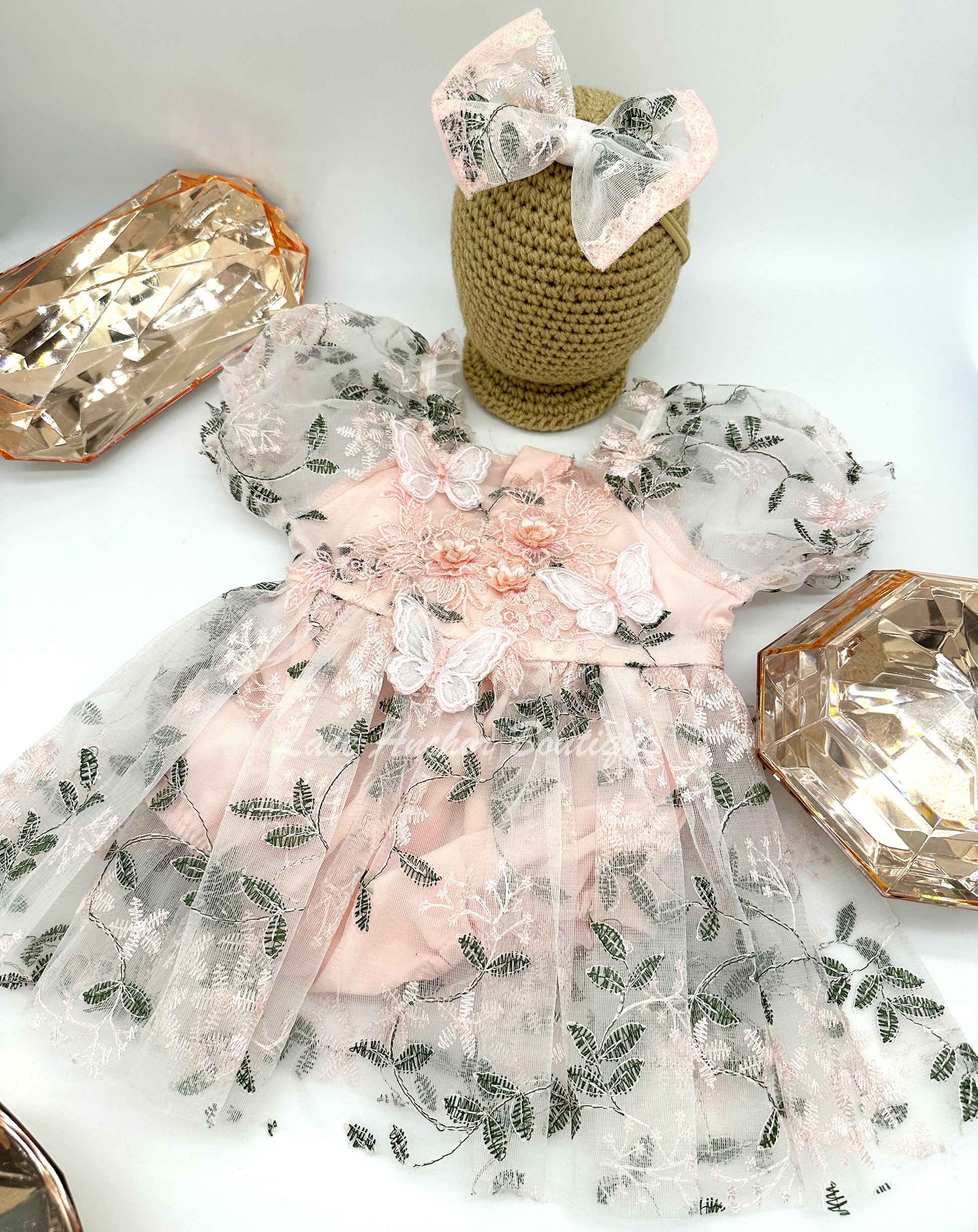 light blush pink embroidered floral print skirted baby girls romper with floral embroidered applique and butterflies with large tied bow on back and puffed short sleeves. Baby toddler flower girl dress.