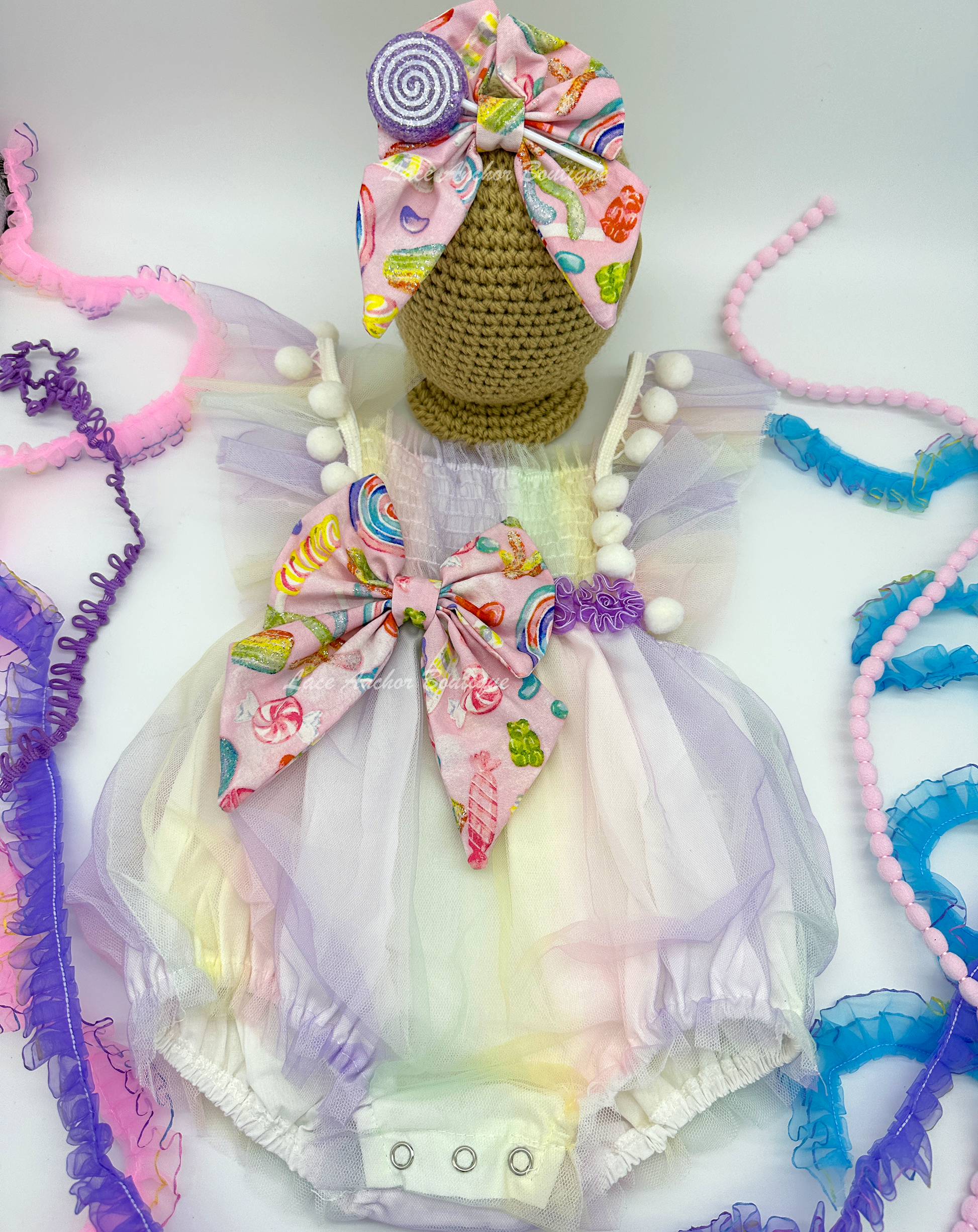 baby girls pastel lilac purple, yellow, blue, blue pink smocked tulle romper with candy themed big bow and matching hair bow with 3D sucker through it. Sweet One Candy Land Themed Outfit for birthday Photoshoots.