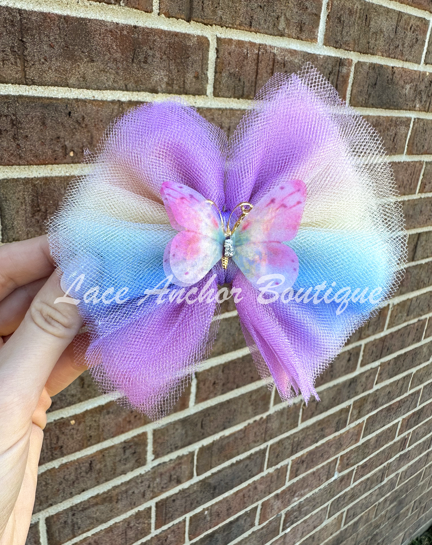 pastel rainbow colored tulle girls hair bow with multi colored butterfly center with gold.