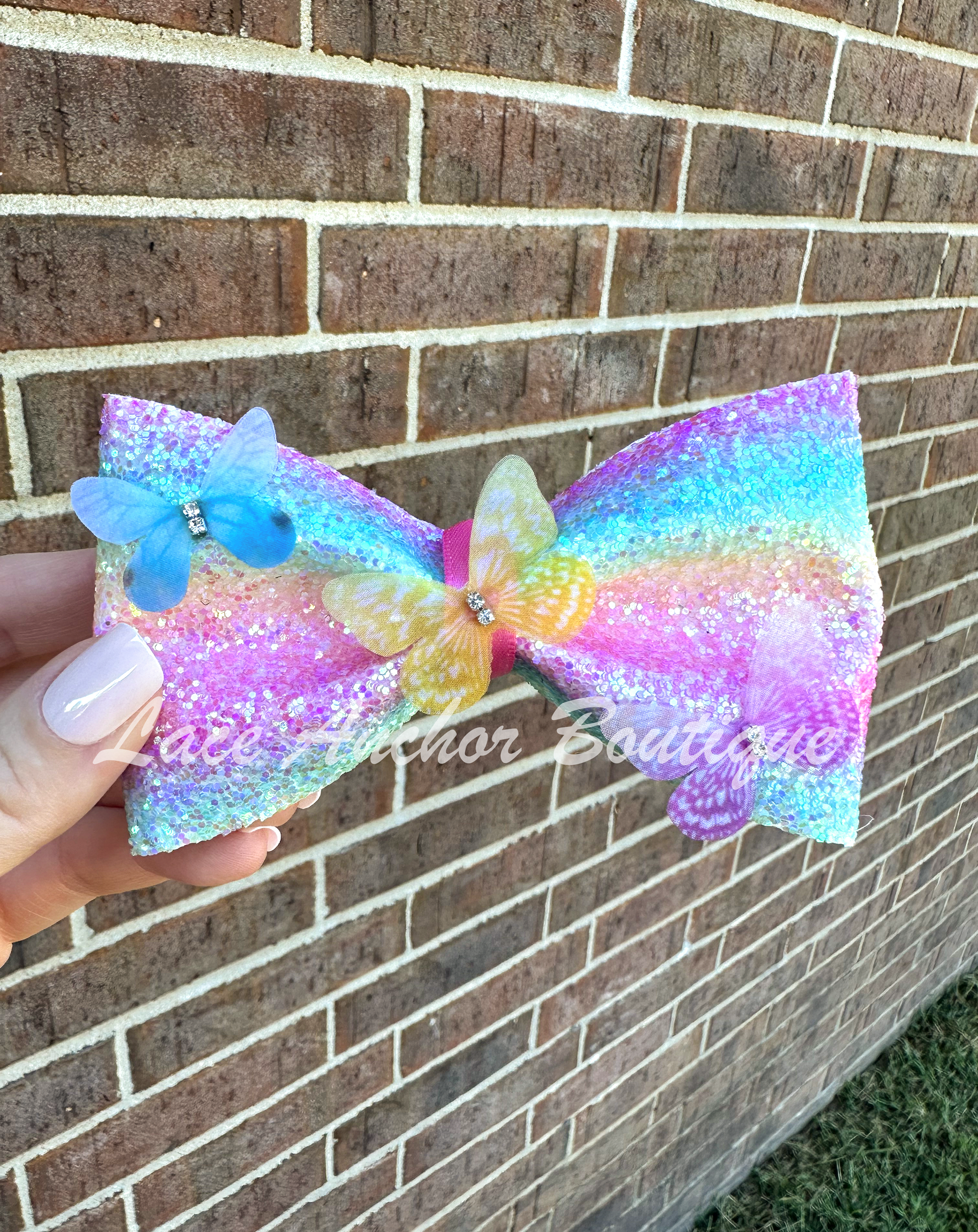 pastel rainbow colored girls hair bow clip with multi colored butterflies and glitter