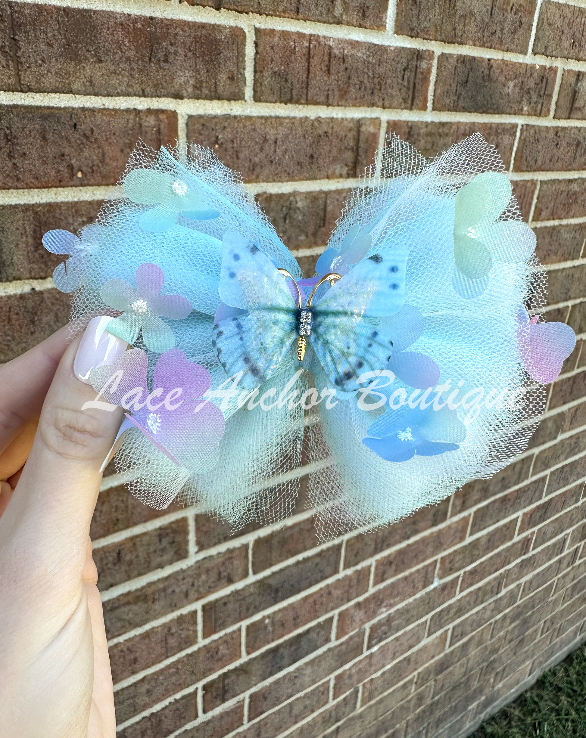 light blue tulle hair bow with flowers and pink and gold butterfly center for toddler girls and up..