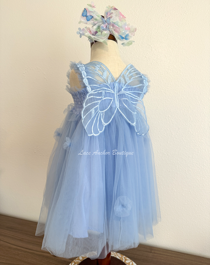 light blue tulle fairy girls dress with smocked top and tulle flowers on skirt. Attached butterfly wings and ruffled straps.