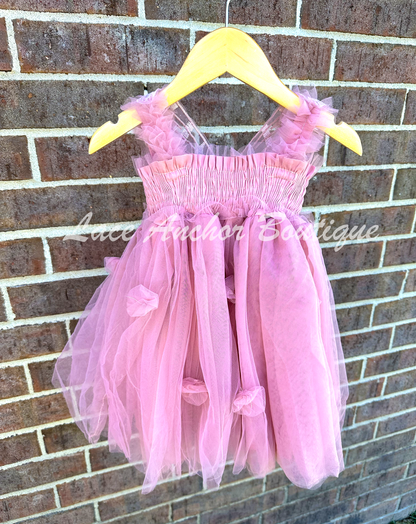 Mauve pink tulle fairy girls dress with smocked top and tulle flowers on skirt. Attached butterfly wings and ruffled straps. Worn by toddler model.