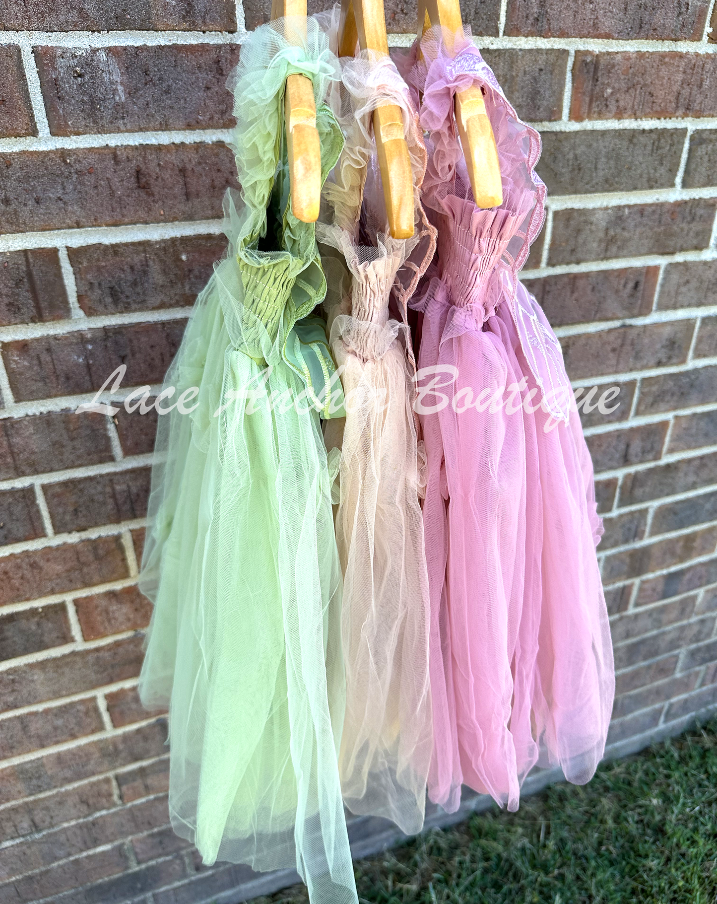 Sage green, champagne beige, and mauve pink tulle fairy girls dresses with smocked top and tulle flowers on skirt. Attached butterfly wings and ruffled straps.