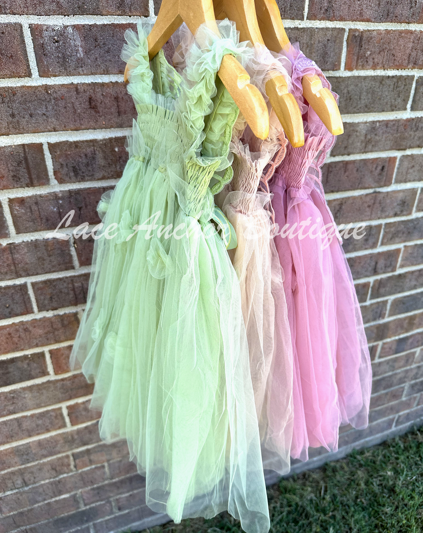 Sage green, champagne beige, and mauve pink tulle fairy girls dresses with smocked top and tulle flowers on skirt. Attached butterfly wings and ruffled straps.