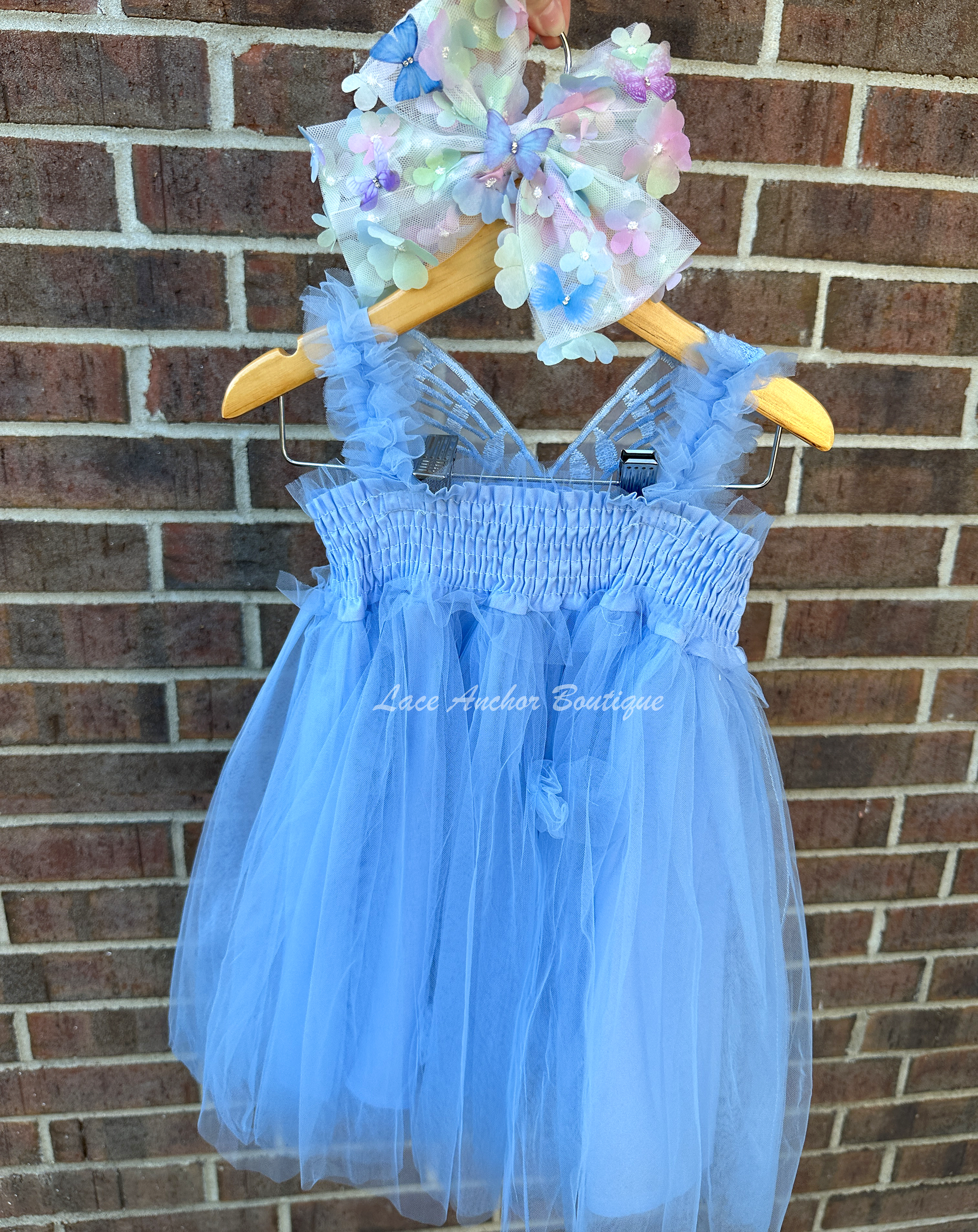 light blue tulle fairy girls dress with smocked top and tulle flowers on skirt. Attached butterfly wings and ruffled straps.