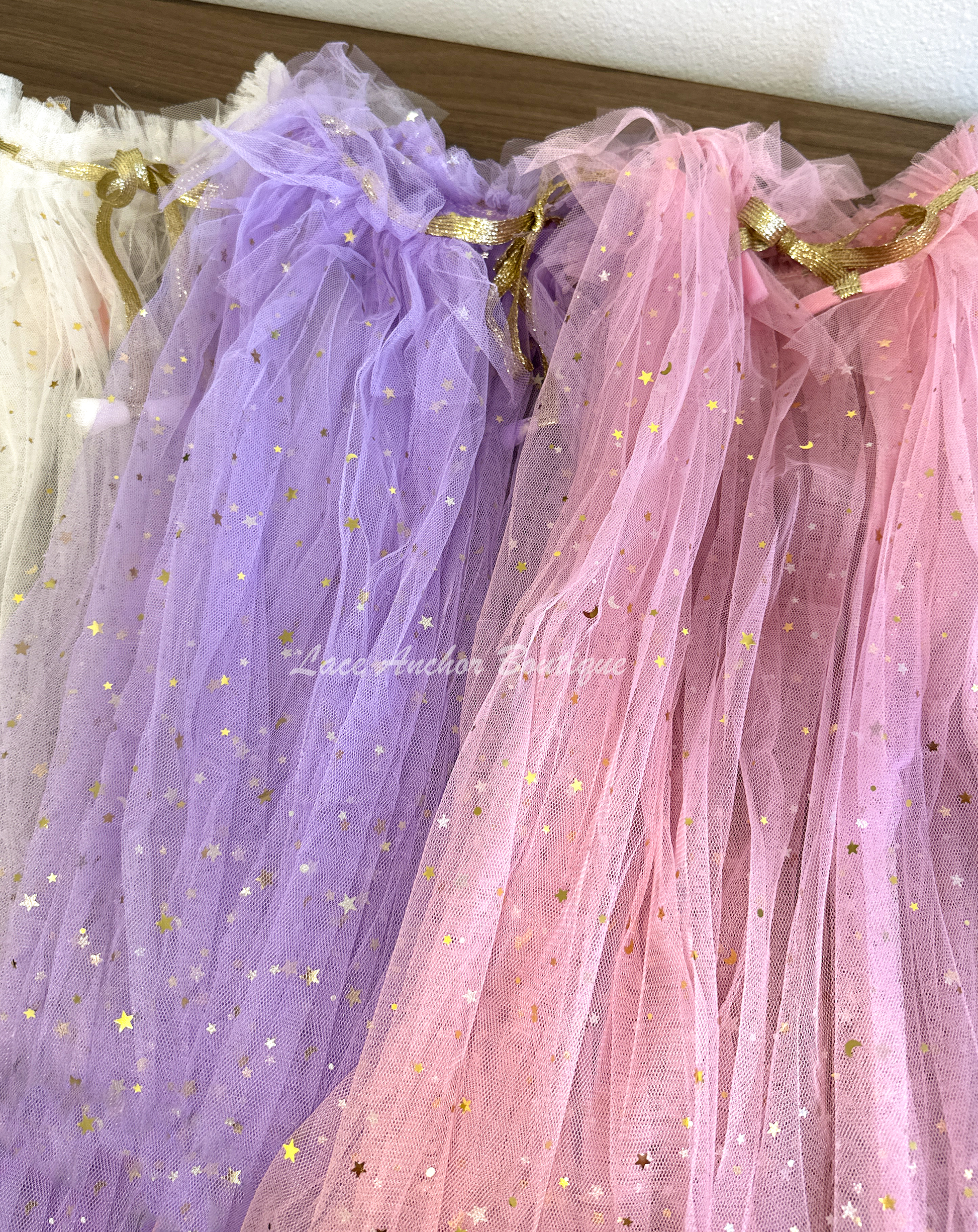 white, purple, and pink tulle girls capes with gold ties and gold metallic stars all over