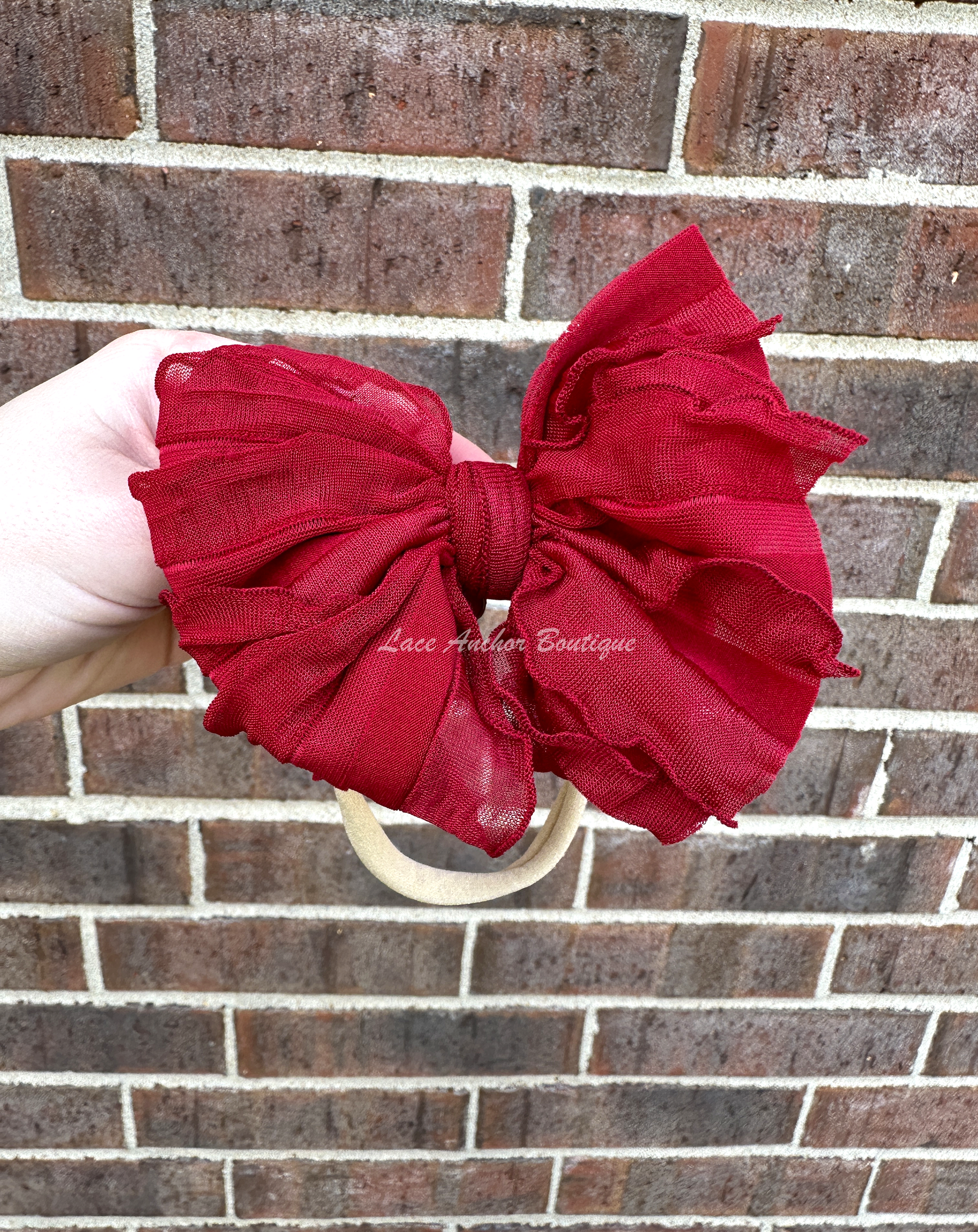 baby headband wrap on nylon band. Burgundy bow with ruffled texture.