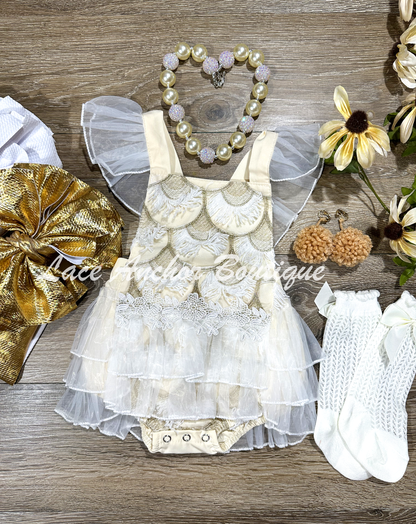 cream ivory baby girls romper outfit. Romper with tied back, fringe embroidered details in gold and white, lace trim, ruffled white layered skirt. First birthday smash cake outfit.