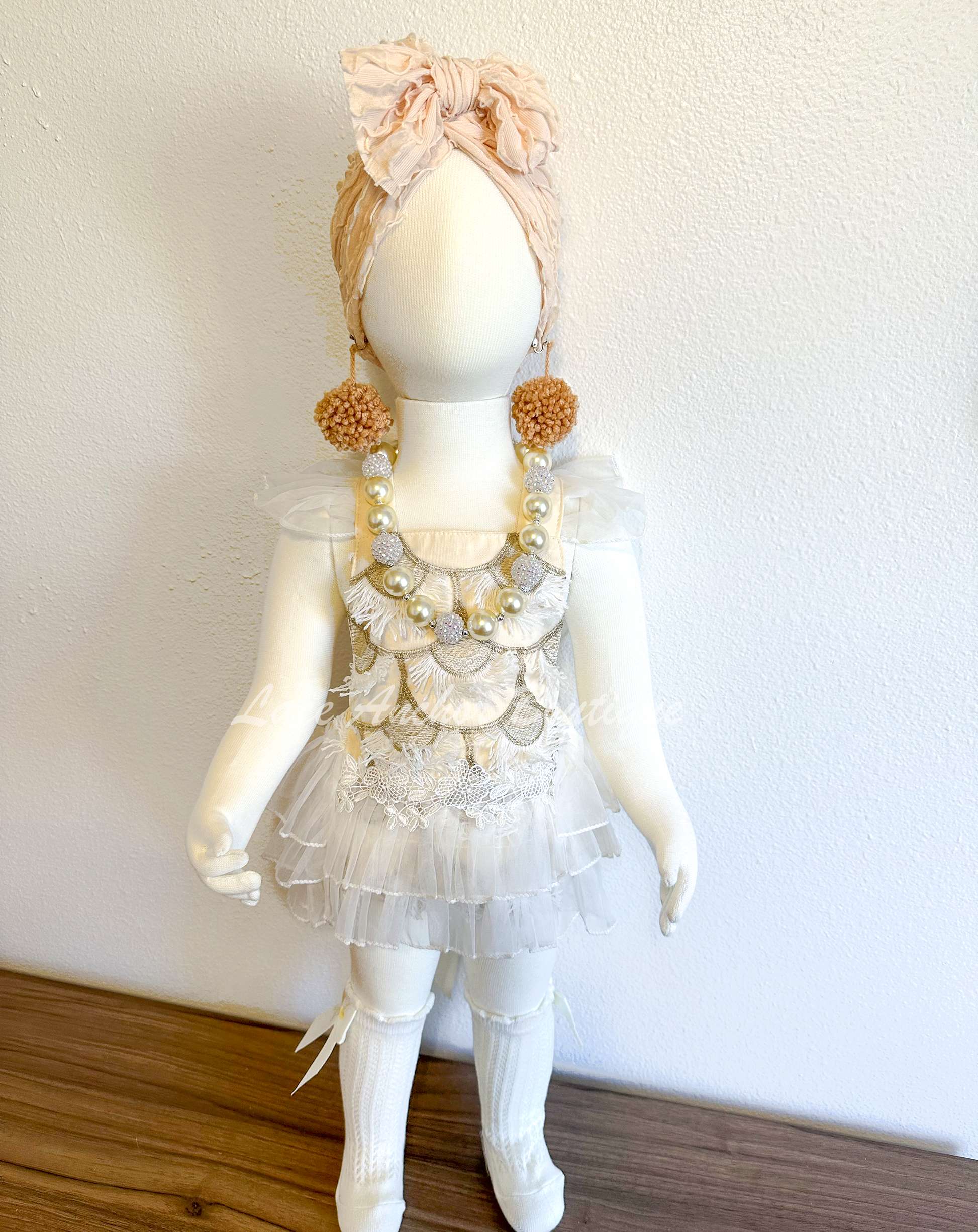 cream ivory baby girls romper outfit. Romper with tied back, fringe embroidered details in gold and white, lace trim, ruffled white layered skirt. First birthday smash cake outfit.
